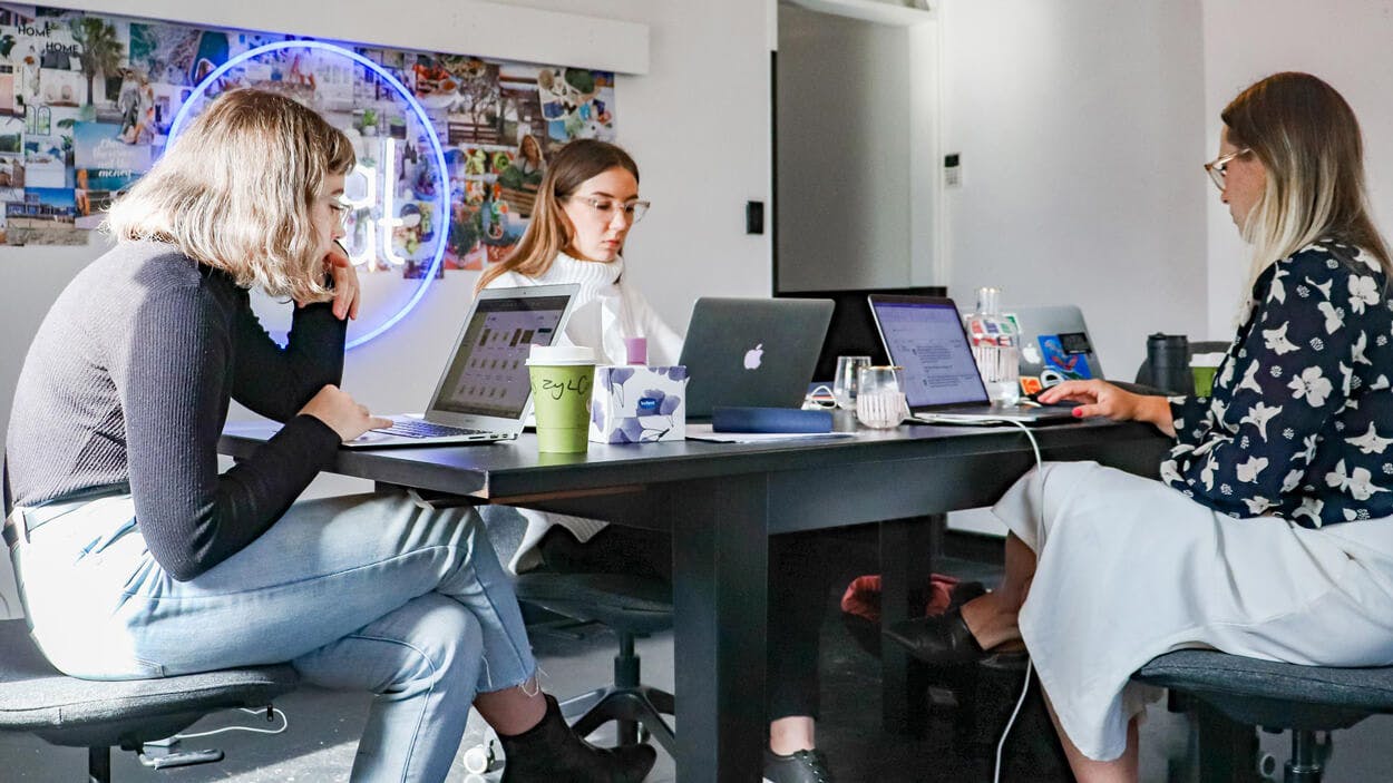 People working around a desk at a mobile app development company in dubai, abu dhabi and the UAE